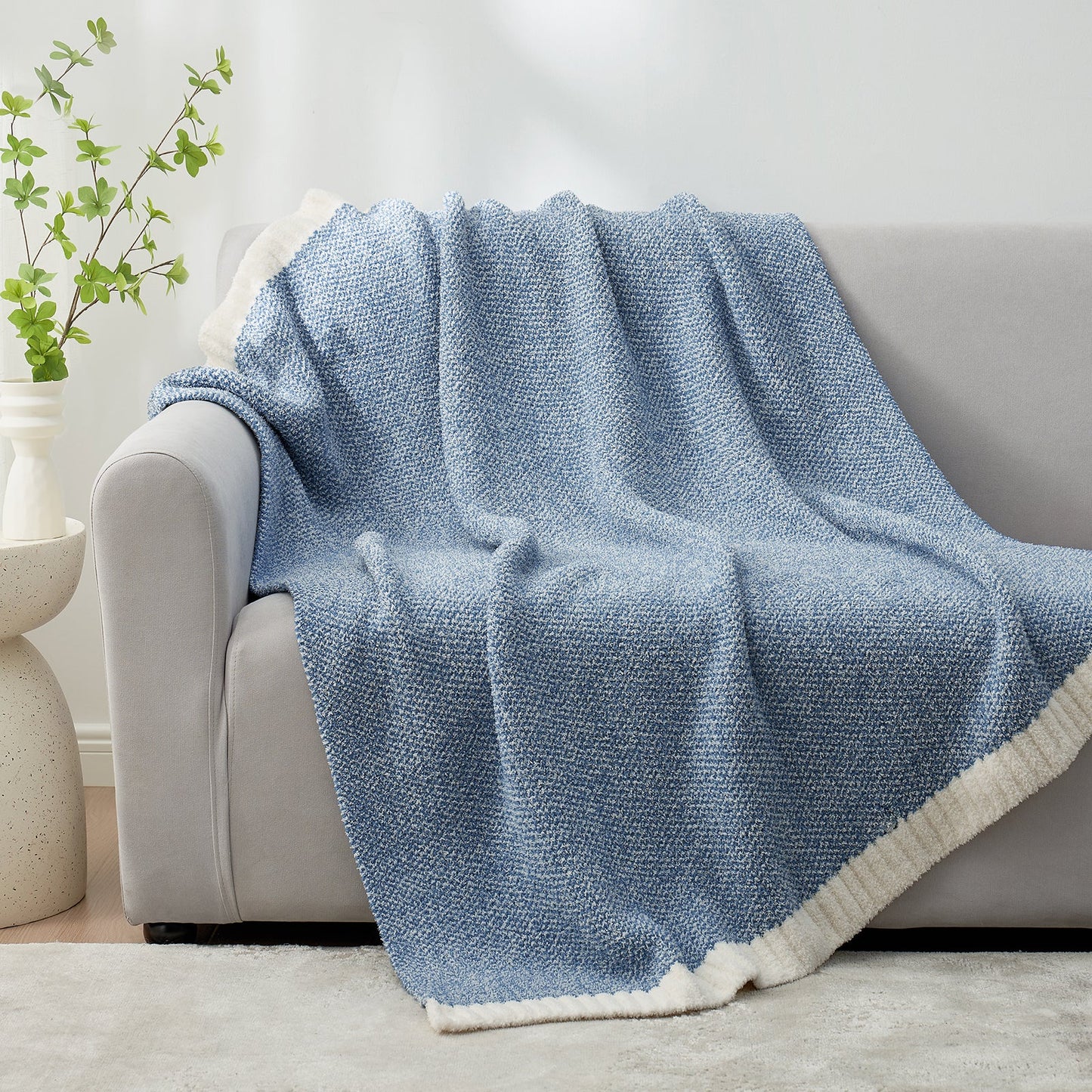 Heather Feather Yarn Throw Blanket in pale blue draped over a sofa, adding warmth, softness and a modern cozy touch to your living room. #Color_Pale Blue